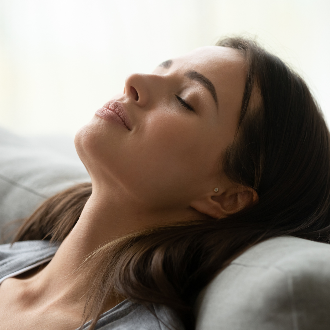 A woman is taking a deep breath and looks peaceful