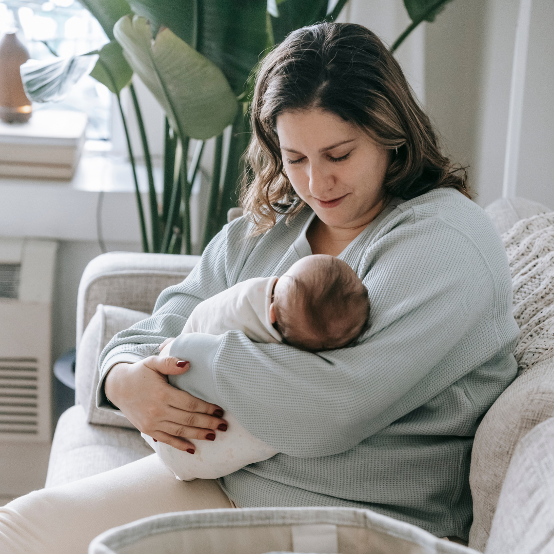 A mom is cradling her newborn infant at home