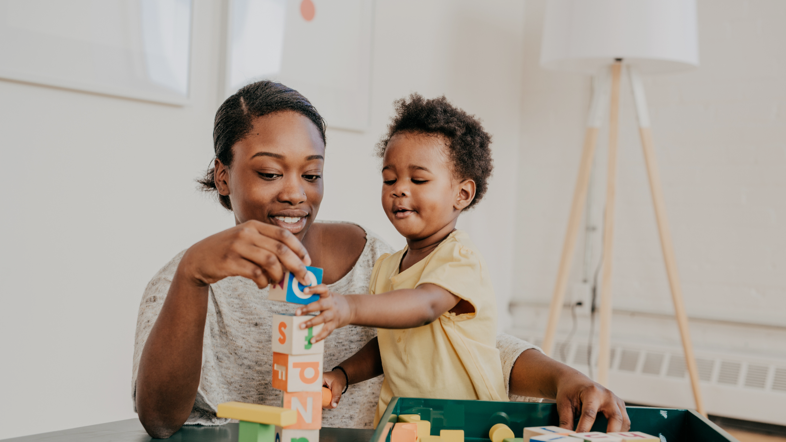 A mother and son are shown playing with building blocks together