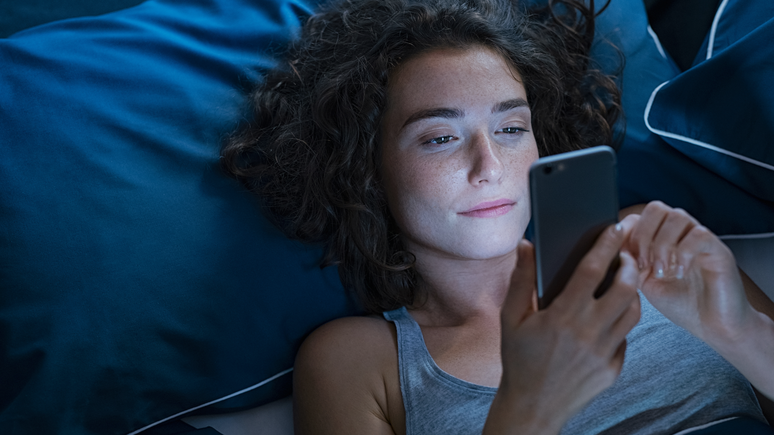 A woman is shown staying up late and looking tired