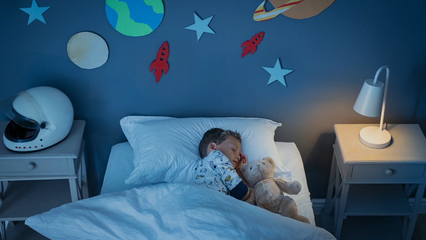 A child looks peaceful as he sleeps in his bed while cuddling his teddy bear