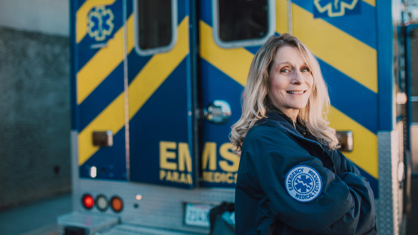 A EMS or MET worker stands proudly next to her ambulance 