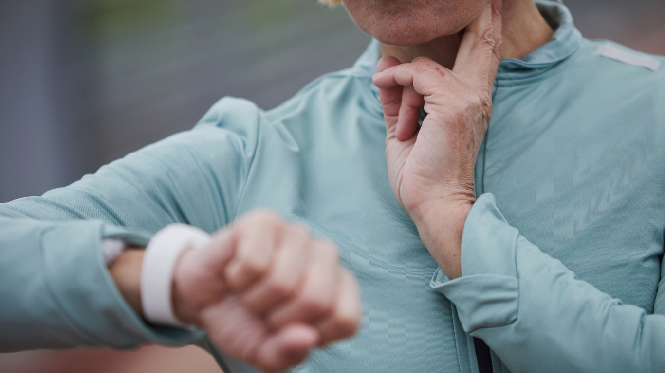 A woman stops her workout to measure and monitor her heart rate